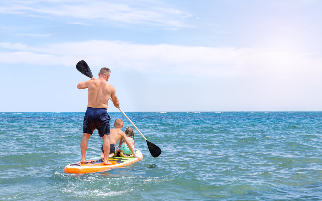 Father and two children ride a SUP board
